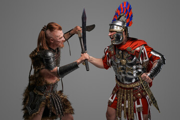 Viking warrior assaults roman centurion against gray background