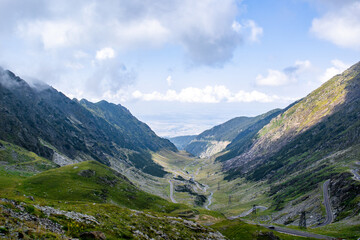 An eerie view from a slope of a mountain of a valley with a road for cars © Adrian Vaida/Wirestock