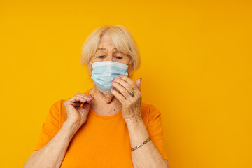 elderly woman in yellow t-shirts in medical masks close-up emotions