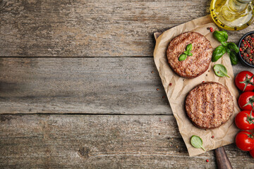 Fototapeta na wymiar Tasty grilled hamburger patties with cherry tomatoes and seasonings on wooden table, flat lay. Space for text
