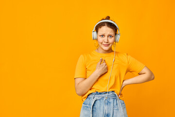 funny girl wearing headphones denim shorts close-up emotions yellow background unaltered