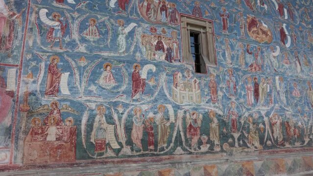 Detail Of Murals On Blue Shade Walls At Voronet Monastery In Suceava, Romania. Panning Right