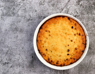 Curd casserole with raisins in a white baking dish on a dark grey background. Top view, flat lay