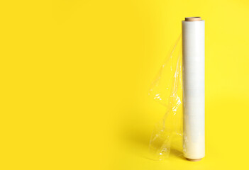 Roll of plastic stretch wrap film on yellow background, space for text