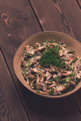 Chicken and mushroom salad, with herbs, seasoned with white sauce, close-up, rustic style,on a wooden table, toned,