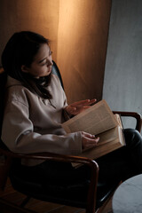 Naklejka premium Shot of young asian female student sitting at table and writing on notebook. Young female student studying in cafe.
