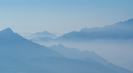 Fototapeta na wymiar Amazing aerial landscape at the Alps in winter season. Foggy and humidity in the air. Italian alps. Silhouette of the mountains and summits