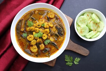 Tangy and spicy Shrimp curry. Tiny prawns curry made using dried mango and Indian spices. garnished with coriander and served with cucumber slices. Copy space.