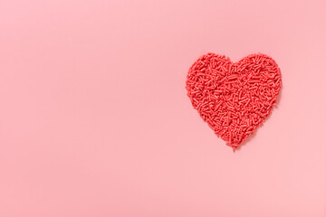 concept of Valentines day greeting with red heart shape from sprinkles over pink background