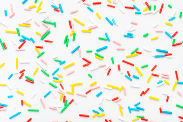 flat lay of colorful sprinkles over white background, festive decoration for banner, poster, flyer, card, postcard, cover, brochure, designers