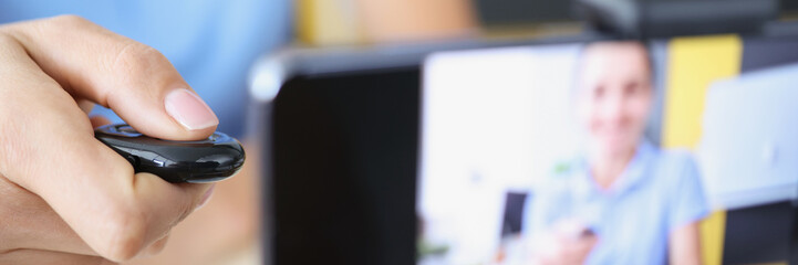 Female hand holding remote control of mobile phone camera on tripod closeup