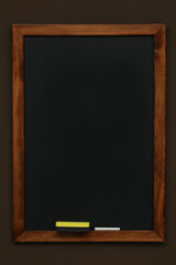 Fototapeta na wymiar Clean black chalkboard hanging on brown wall
