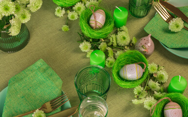 Fototapeta na wymiar Set table with Easter decoration - eggs in nests and flowers.