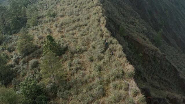 Hikers Walking On Steep Rocky Trail Overlooking Crater Of El Chichon Volcano In Chiapas, Mexico. aerial drone, tilt-down pan right
