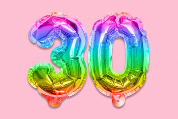 Rainbow foil balloon number, digit thirty on a pink background. Birthday greeting card with inscription 30. Anniversary concept. Top view. Numerical digit. Celebration event, template.