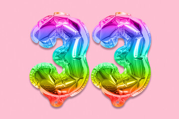 Rainbow foil balloon number, digit thirty three on a pink background. Birthday greeting card with inscription 33. Top view. Numerical digit. Celebration event, template.