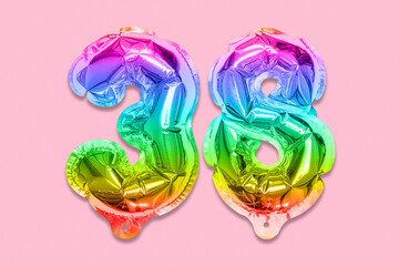 Rainbow foil balloon number, digit thirty eight on a pink background. Birthday greeting card with inscription 38. Top view. Numerical digit. Celebration event, template.