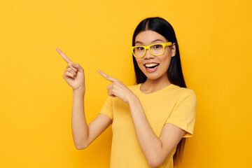 Obraz premium woman with Asian appearance in glasses gesturing with hands copy-space yellow background unaltered