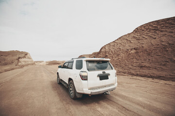 Fototapeta na wymiar Driving white off road car crossing in the desert road trip