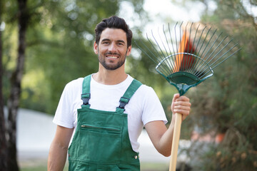 portrait of young man holding rake smiling