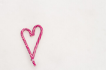 Festive minimalistic white background. A heart of sweet pink striped candies on a white snow background. Love. Valentine. Creative gift ideas for Valentine's Day. The 14th of February. Photo with a