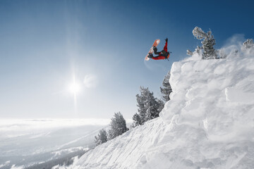 Snowboarder making high jump in clear blue sunny sky above mountains