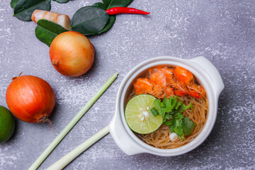 Shrimp potted with vermicelli is served in a white ceramic bowl with spices, chili, lemon, onion, kaffir lime leaves and galangal.