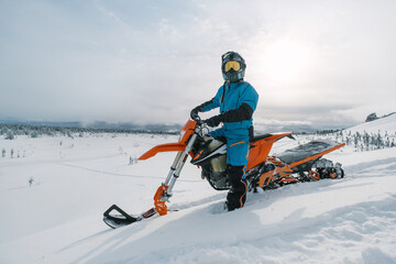 Snowbike rider in mountain valley in beautiful snow powder. Modify dirt bike with snow splashes and...