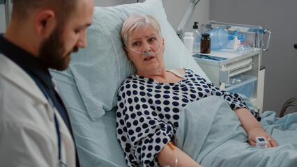 Close up of elder patient laying in bed and talking to medic for healthcare treatment. Doctor...