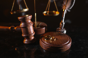 Obraz na płótnie Canvas Divorce and law concept. Judge gavel and gold rings on a glossy table