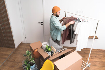 Adult men hanging clothes on a clothes rack in new home on moving day.
