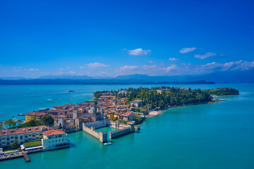 The flag of Italy on the main tower of the castle. 
Aerial photography with drone, Rocca Scaligera Castle in Sirmione. Garda, Italy. Aerial view of Sirmione. Sirmione Castle, Lake Garda, Italy.