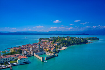 Fototapeta na wymiar Sirmione Castle, Lake Garda, Italy. The flag of Italy on the main tower of the castle. Aerial photography with drone, Rocca Scaligera Castle in Sirmione. Garda, Italy. Aerial view of Sirmione. 