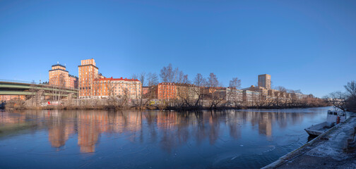 Panorama view with the bridge St Eriksbron over the canal Karlbergskanalen with ice floes, apartment houses and offices and the traffic route Karlbergsleden a sunny winter day in Stockholm
