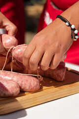 manos acomodando salchichas en el asador , para cocinarlas al carbón en un día soleado