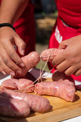 manos acomodando salchichas en el asador , para cocinarlas al carbón en un día soleado