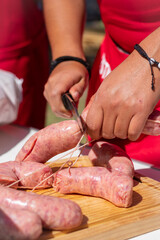 manos acomodando salchichas en el asador , para cocinarlas al carbón en un día soleado