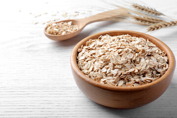 Oatmeal, bowl and spoon on white wooden table. Space for text