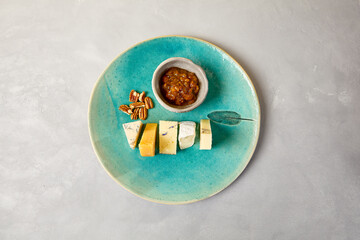 Cheese platter on blue ceramic plate. Cheeseboard on handmade dinner plate in modern style....