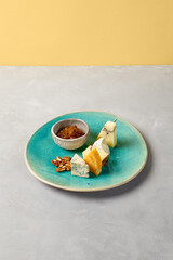 Cheese platter on blue ceramic plate. Cheeseboard on handmade dinner plate in modern style. Different cheese on ceramic dishware in minimal style.