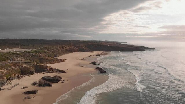 Remote golden sand beach on Atlantic coastline, Portugal; aerial pullback