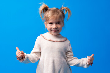 Cute little girl showing thumb up on blue background