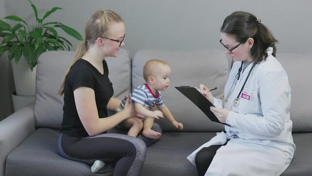 pediatrician woman doing check up baby with mother home. doctor stethoscope, visit infant patient, fill patient form, holding clipboard, listens parent complaints , making notes, medical appointment