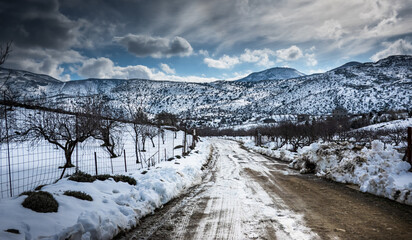 Country road with mountains against cloudy sky during winter