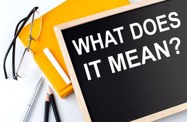 WHAT DOES IT MEAN text on the blackboard with notepad , pen, pencil