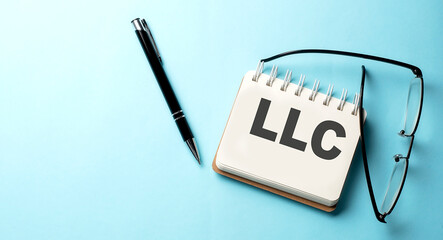 LLC text written on a notepad on the blue background