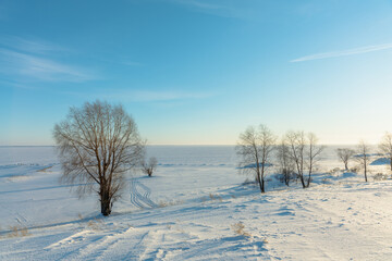 Snow covered winter field with trees. Winter landscape. Beautiful winter nature. Frozen water reservoir.