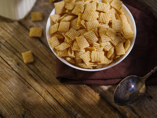 Close-up. Crispy whole-grain pads in a bowl on a brown napkin, with a jug of milk in the background. Wooden background. Express breakfasts, ecology, healthy lifestyle.