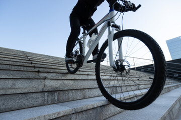 Woman free rider riding bike going down city stairs