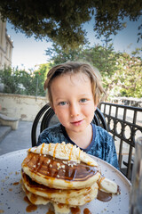Boy eating pancake at outdoor cafe